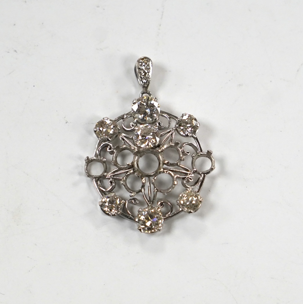 A white metal and diamond cluster set circular pendant (seven stones missing), largest stone diameter approx. 5.6mm, overall 35mm, gross weight 6 grams.